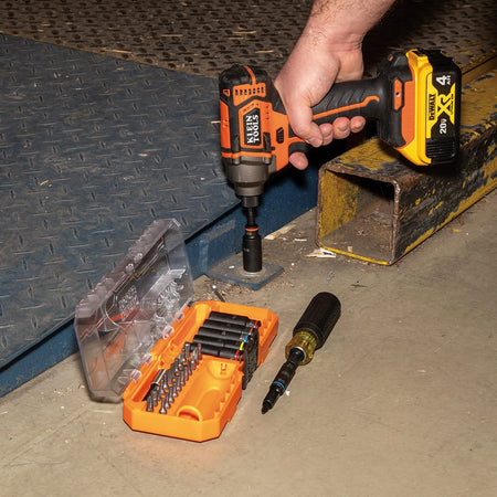 Worker driving a heavy steel flange bolt using an impact driver equipped with a 9/16-inch deep socket from the Klein 32502HD kit.