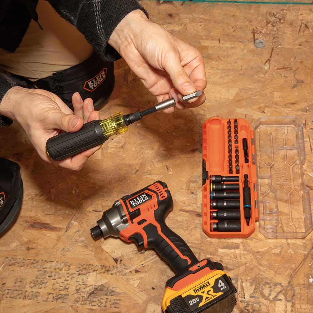 Electrician inserting a 1/4-inch slotted bit into the magnetic bit holder attached to the Klein Cushion-Grip multi-tool handle.