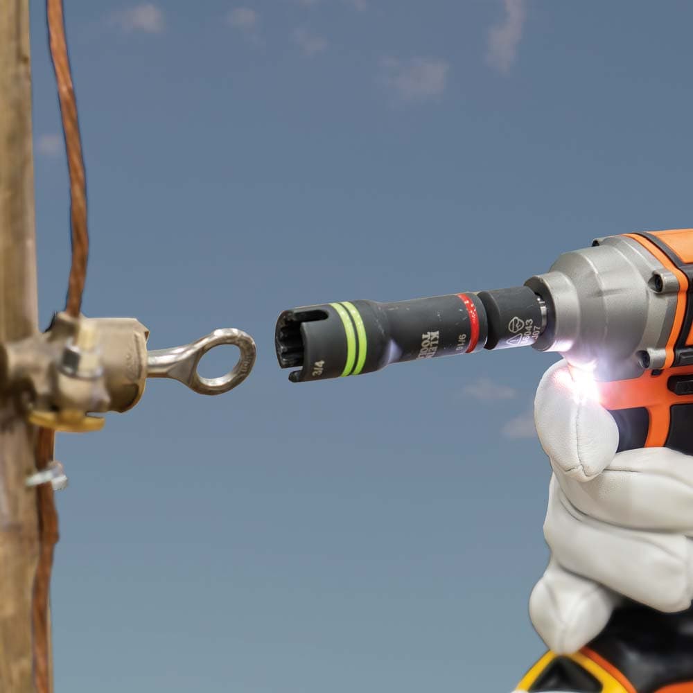 Utility technician aligning the side slot of a Klein 66044 socket over an overhead hot-line clamp loop on a power pole.