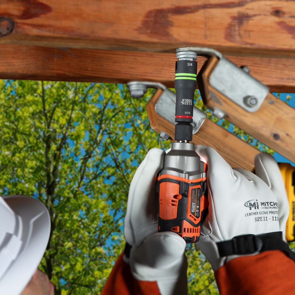 Utility worker using the 66044 flip socket on a power impact wrench to secure mounting brackets on an overhead cross-arm assembly.