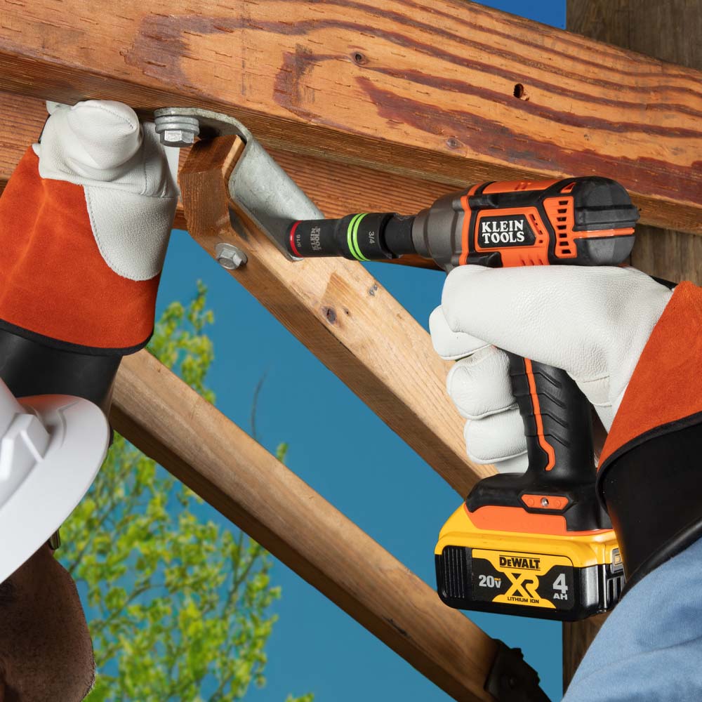 Electric utility technician driving structural hardware underneath a timber cross-arm using a Klein 3-in-1 slotted impact socket.