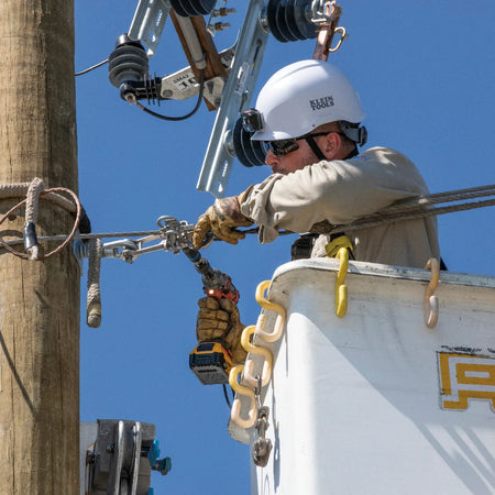 Power utility lineman in a bucket truck using the Klein 66031 socket on an impact driver to service overhead line hardware.