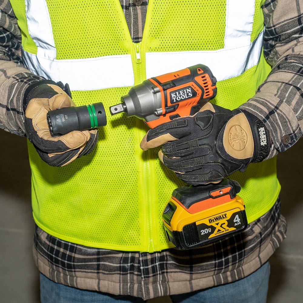 Lineman attaching a 1-1/8 by 15/16-inch slotted impact socket onto a 1/2-inch square drive cordless wrench for pole hardware jobs.