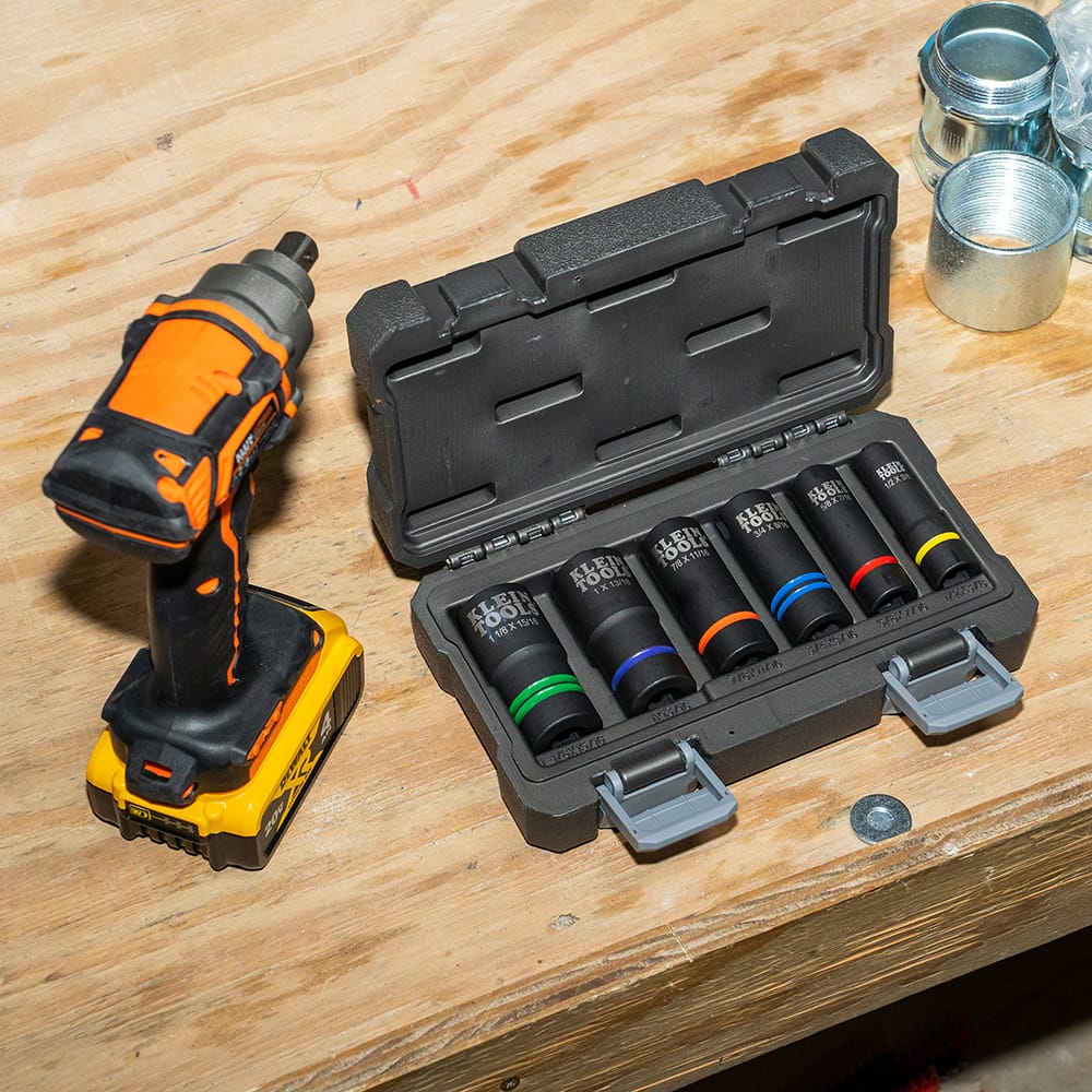 Klein 66090 6-piece slotted socket set organized in its hard-shell storage case resting on a jobsite workbench next to an impact driver.