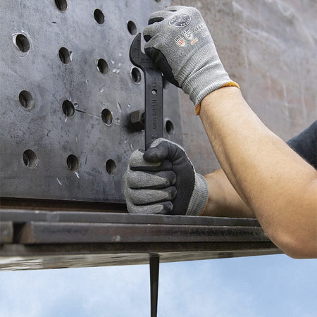 Ironworker driving the tapered handle of the Klein 3212TT spud wrench into overlapping gusset plate holes to leverage steel beams into alignment.