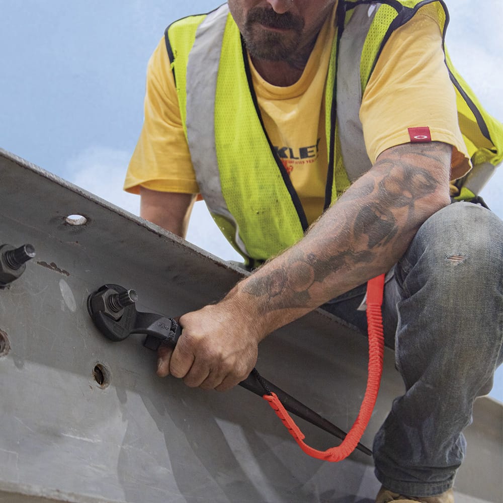 Ironworker securing a heavy structural beam bolt using the 60-degree offset head of a tethered Klein 3212TT spud wrench.