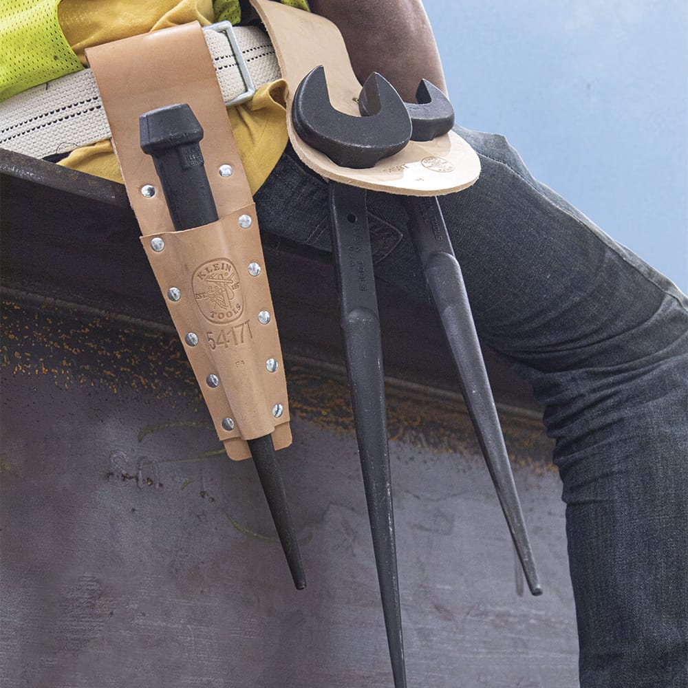 Ironworker rig setup showing two Klein spud wrenches and a bull pin stored in leather belt holsters for quick access on steel structures.