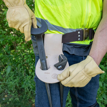 Gloved ironworker drawing a spud wrench from the Klein 5459T dual-pocket leather holster mounted on a 3.5-inch work belt.