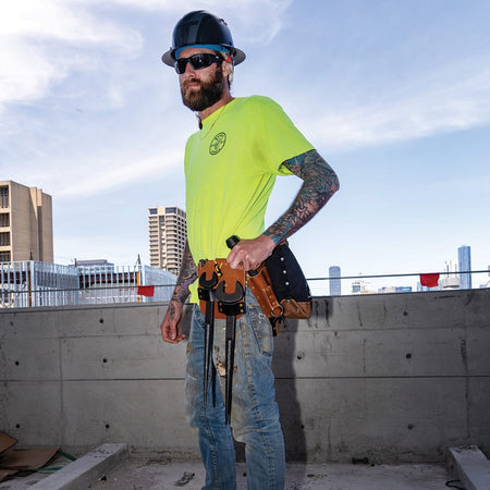 Ironworker on an elevated jobsite wearing a tool belt with the Klein 5860 dual-pocket leather holder carrying two spud wrenches.