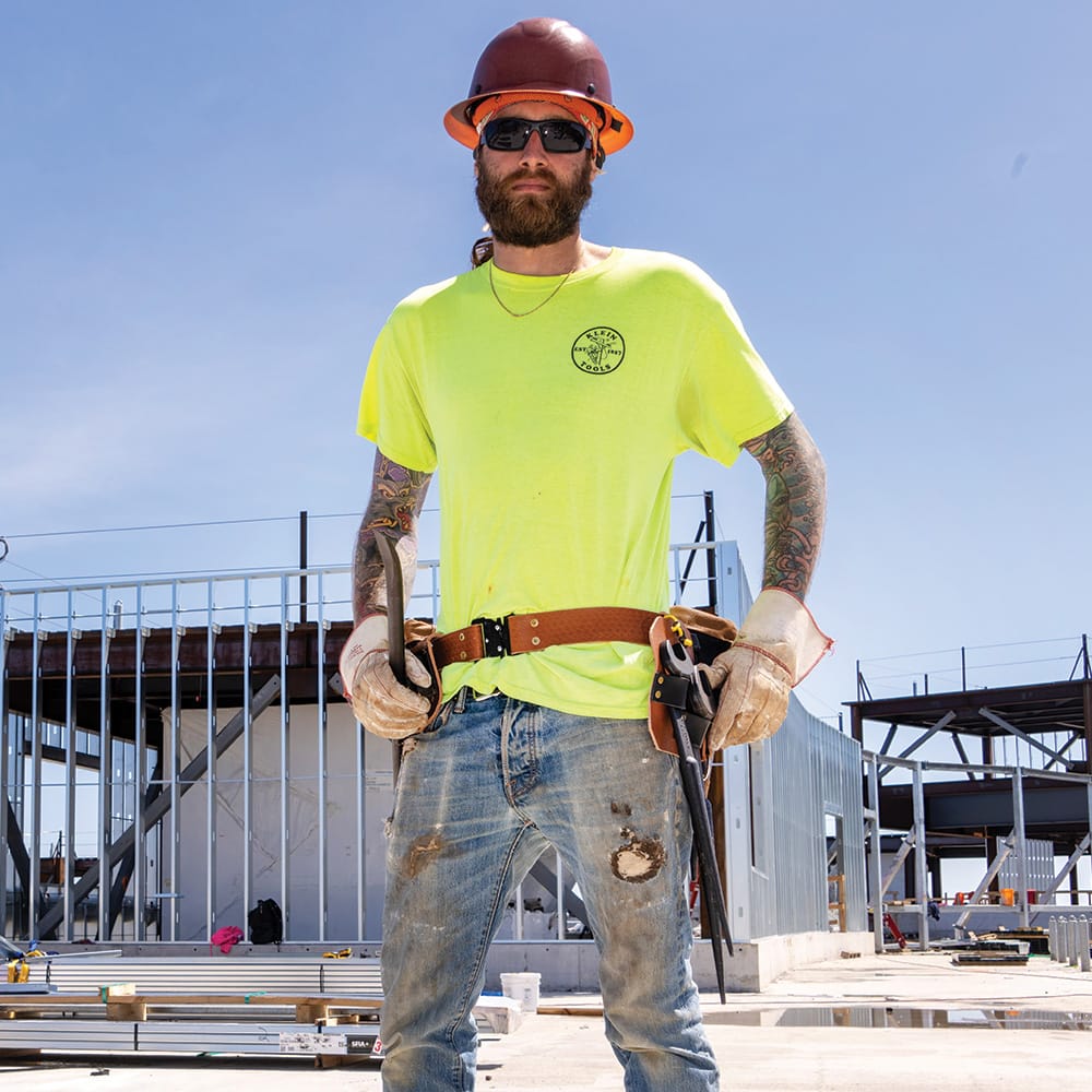 Ironworker at a commercial structural steel jobsite with the Klein 5860 leather dual spud wrench holder positioned at the hip for quick access.