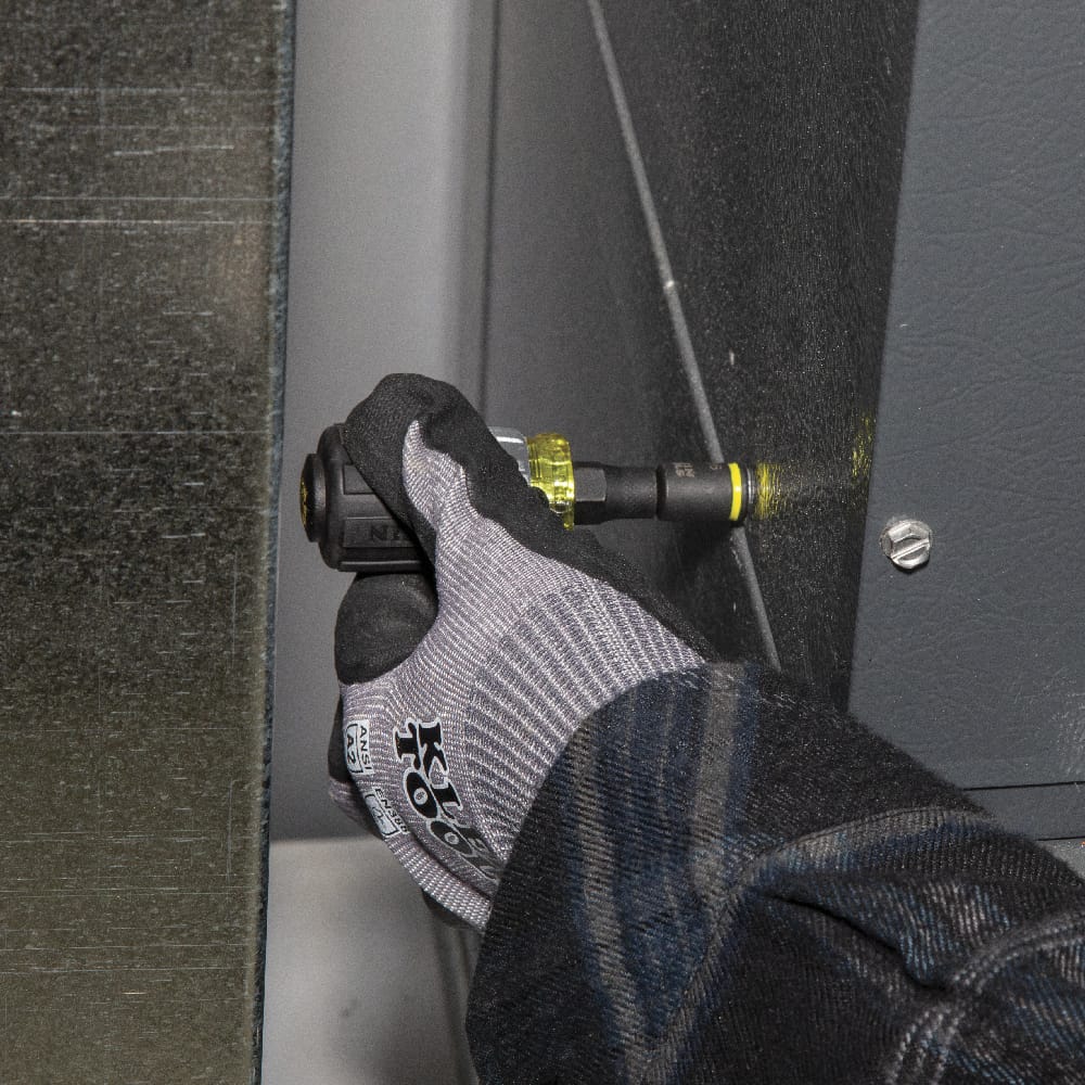 Technician using the Klein Tools 32561HDRT ratcheting stubby driver to tighten a hex head screw inside a tight HVAC metal equipment cabinet.