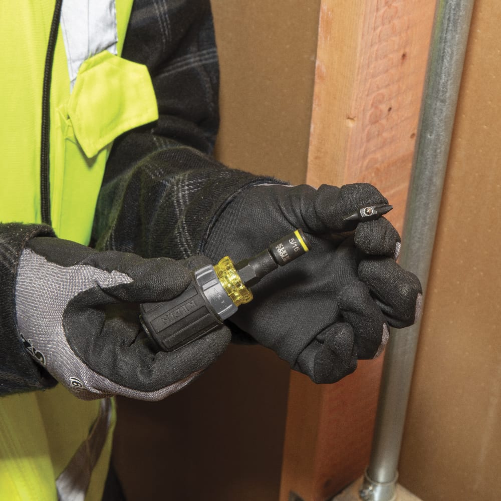 Electrician swapping a double-ended Phillips screwdriver bit into the 5/16-inch nut driver socket on the Klein 32561HDRT stubby handle.