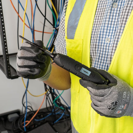 Electrician holding the Klein 57032 torque screwdriver loaded with a Phillips bit to perform calibrated terminal block torquing.
