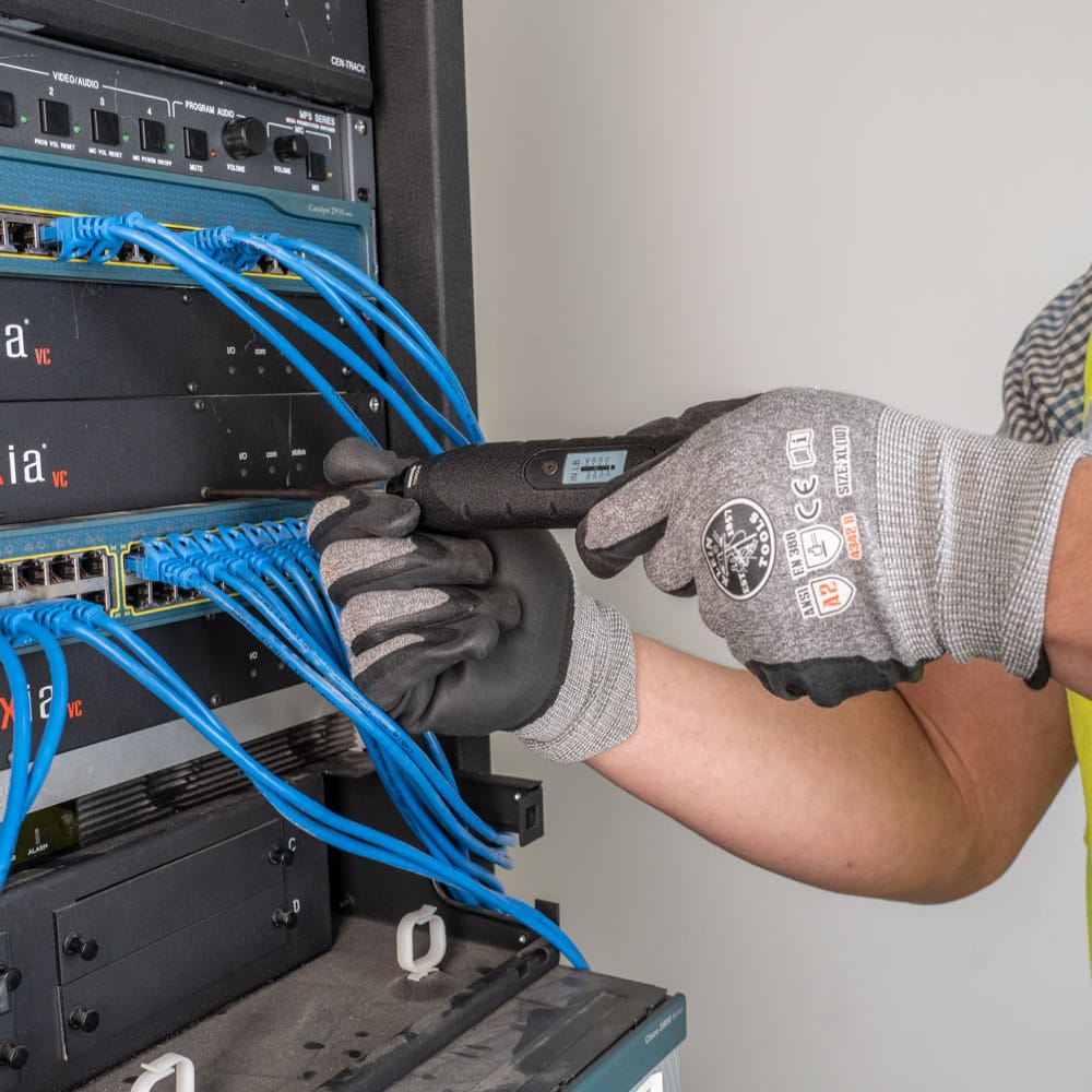 Technician using the Klein 57032 torque screwdriver to secure low-voltage rack server panel screws without over-tightening.