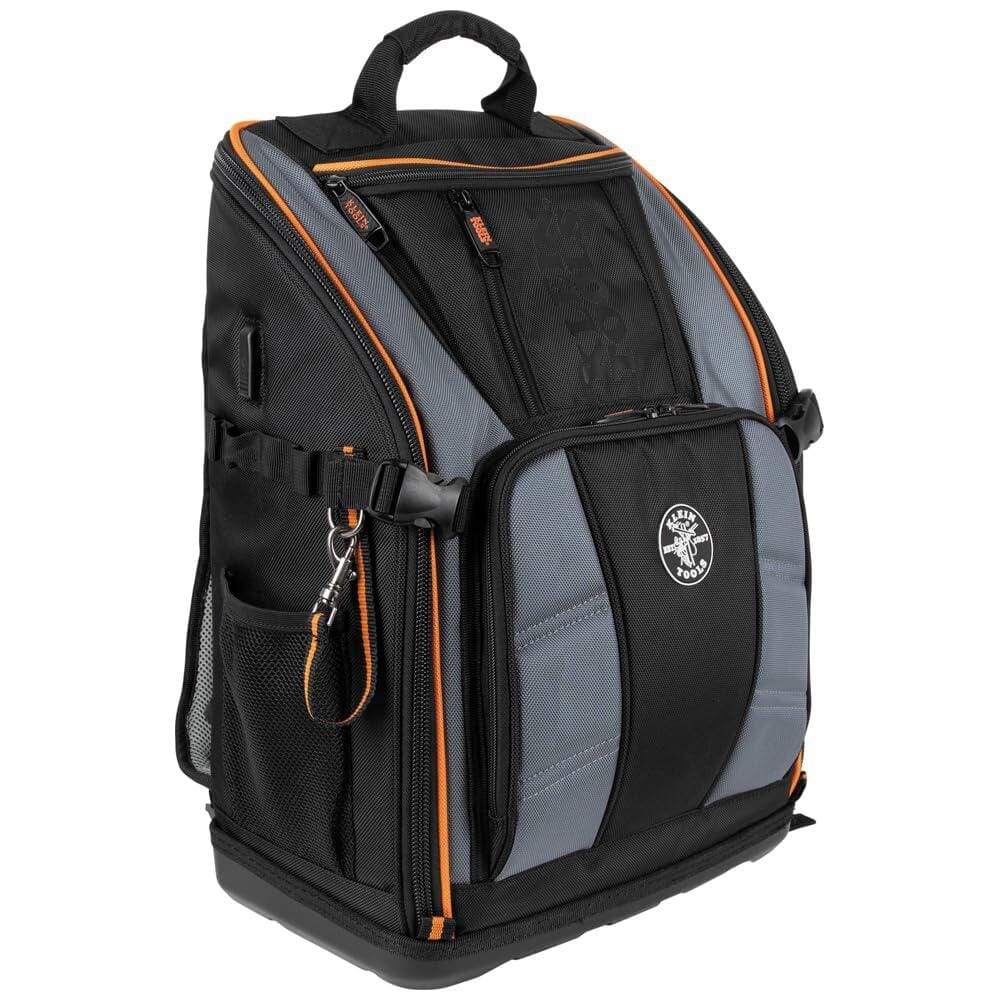 Front three-quarter view of the closed Klein Tools Tradesman Pro Tool Backpack, showcasing its heavy-duty construction, orange accents, and molded base.