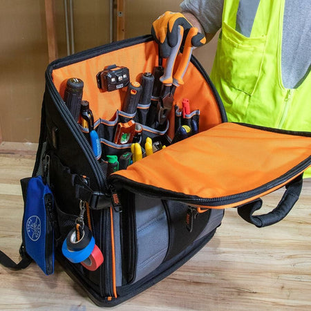 Interior view of the backpack unzipped halfway for quick access, showing various screwdrivers, pliers, and other small hand tools secured in the main pocket panel.