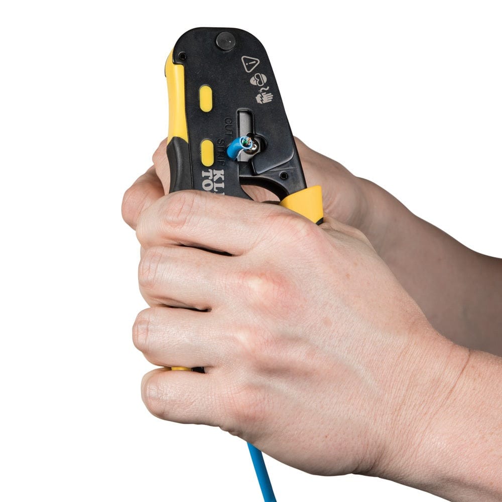 Close-up action shot of the tool being used to strip the outer jacket of a blue data cable using the integrated stripping port located near the handle pivot.