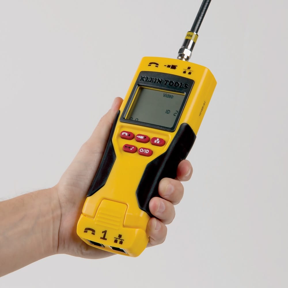 A clear close-up of the Klein Tools VDV501-825 Scout Pro 2 LT tester held in hand on a white background, with a black coax cable connected to the top F-connector, performing a video ID test showing Video and ID 2 on the screen.