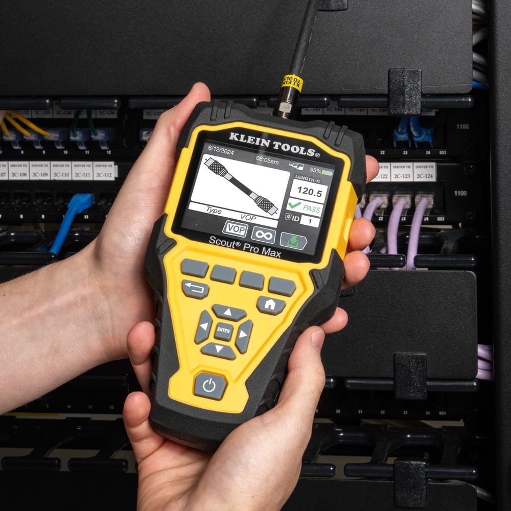 Action shot of a technician using the Scout Pro Max tester to trace an individual line within a dense bundle of blue CAT6 Ethernet cables. The device is connected to the network run, illustrating how professionals use digital toning and TDR technology to isolate specific cables in complex IT infrastructure.