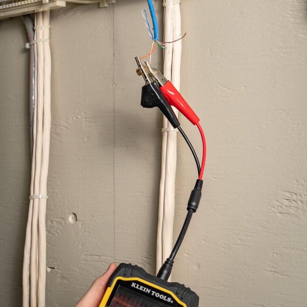 Close-up action shot of a professional using the Klein Tools Scout Pro Max to test a residential network run. The device is shown with its interactive interface active, providing a comprehensive diagnostic overview of the twisted-pair cable's integrity, length, and mapping status.