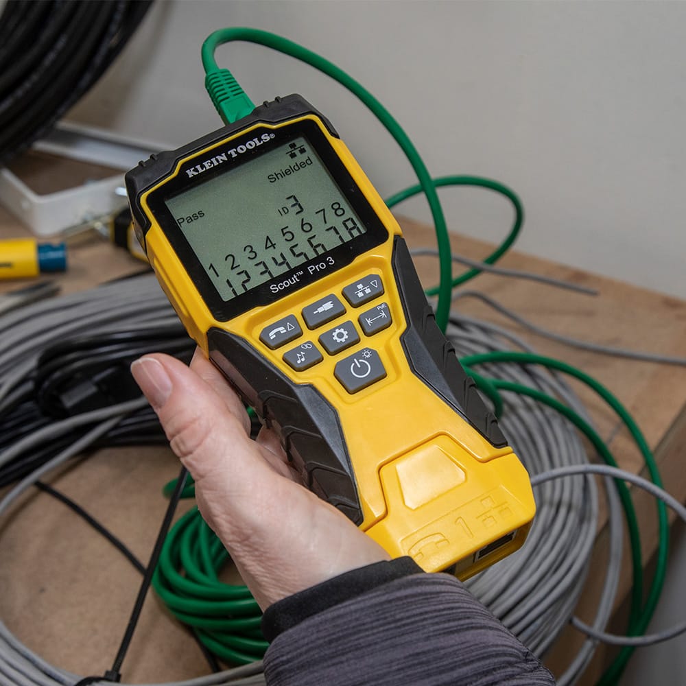 Action shot of the Scout Pro 3 performing a wiremap test on a shielded CAT6 cable. The display confirms a Pass status for a shielded line at remote ID location #3, highlighting the tool's effectiveness in verifying complex industrial network shielding.