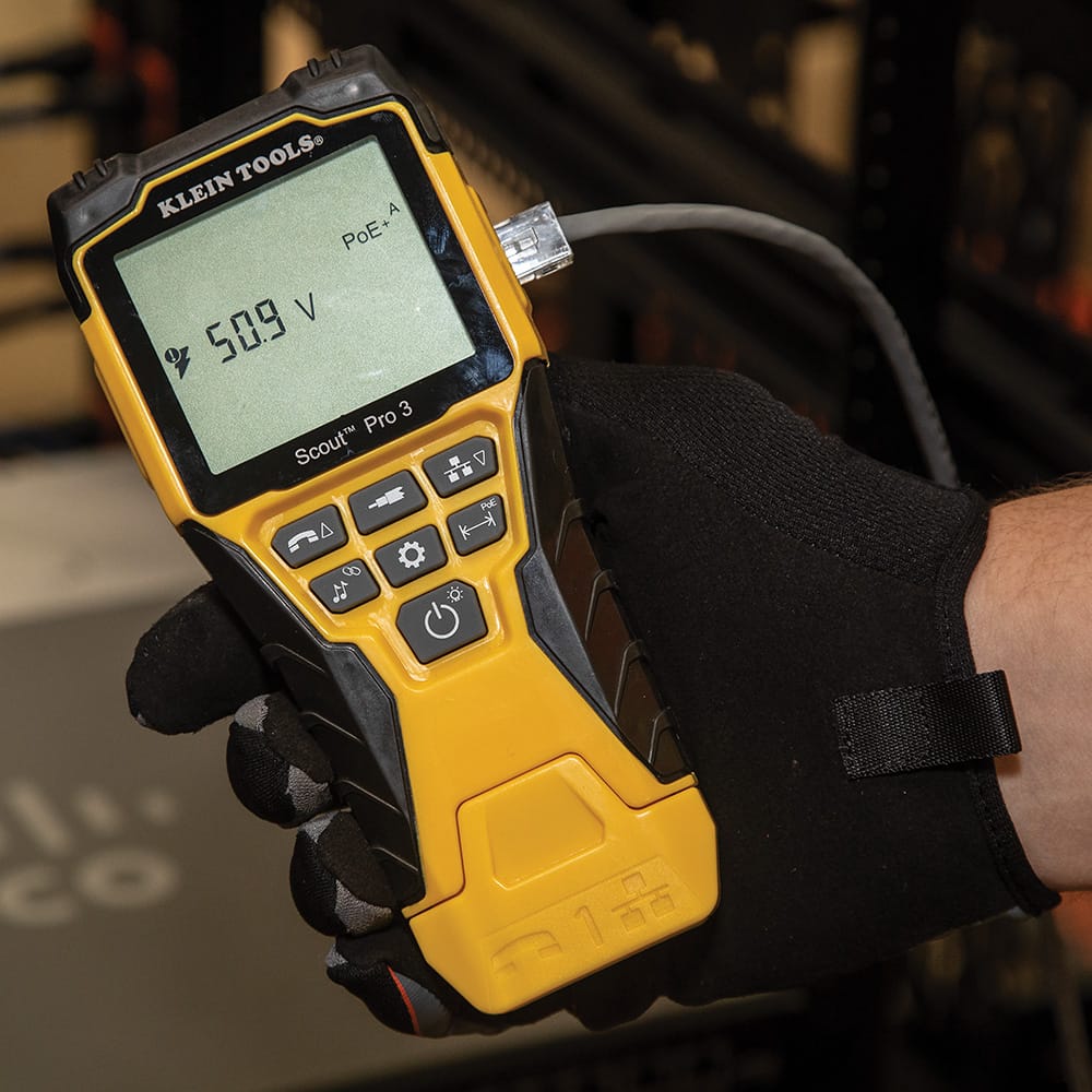 Action shot of a technician testing a live network line for Power over Ethernet. The Scout Pro 3 screen displays a reading of 50.9 Volts and identifies the source as PoE+ Type A, confirming the tester's advanced active-network diagnostic capabilities.