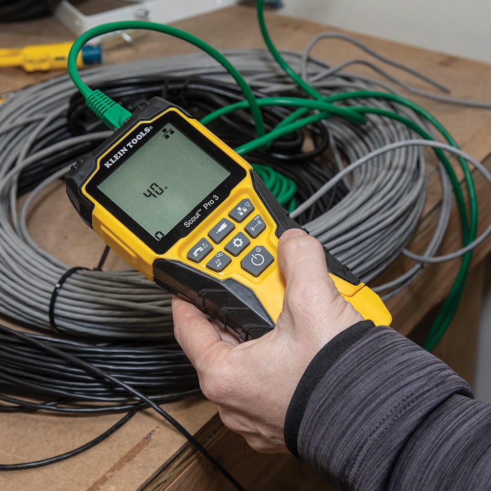 Action shot of a technician measuring a large coil of cable using the Scout Pro 3. The high-resolution display shows a length measurement of 40 feet, demonstrating the tool's ability to verify cable run distances and estimate remaining inventory on a spool.