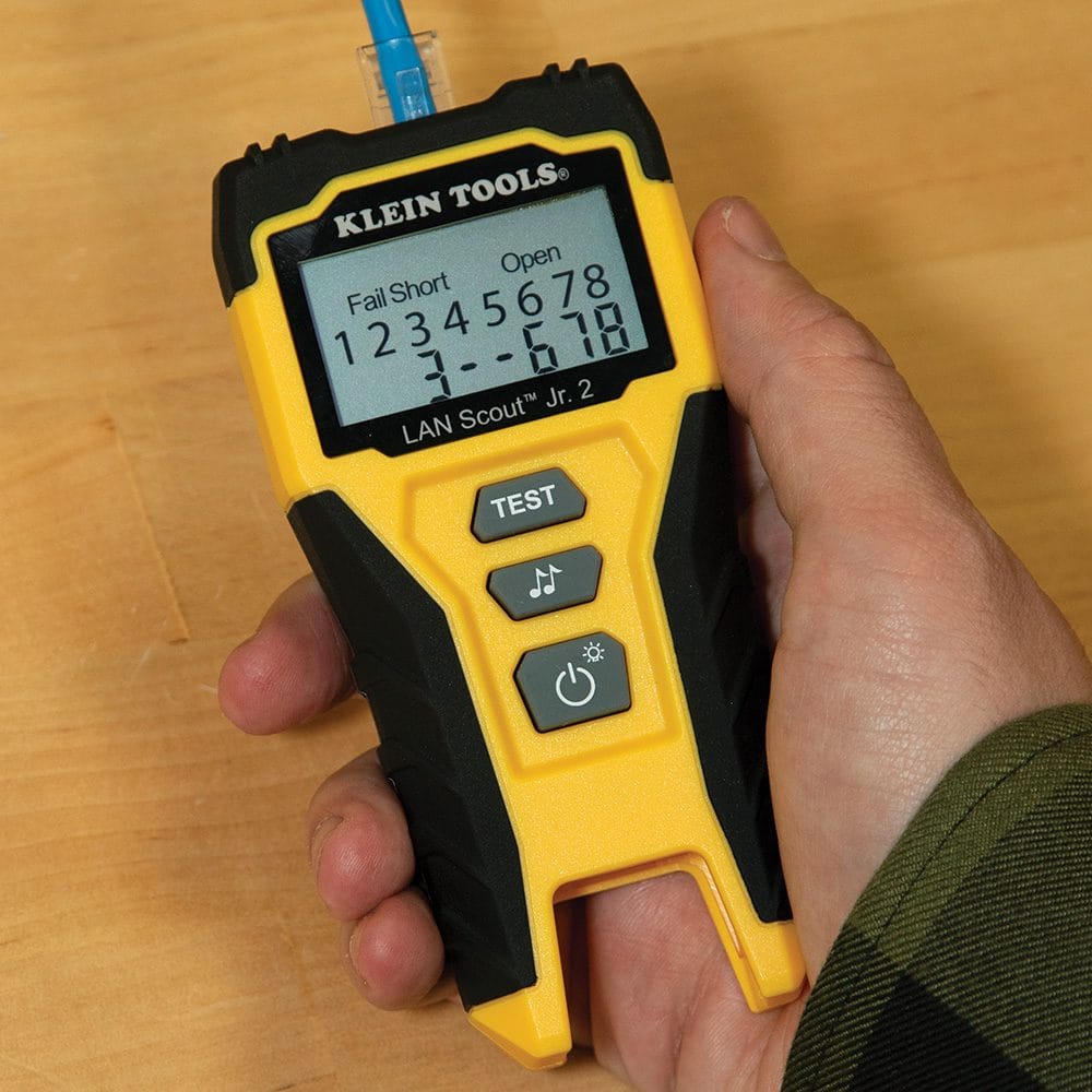 A close-up handheld view of the tester display identifying Fail Short and Open faults on a specific Ethernet cable termination.