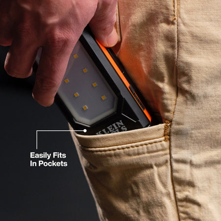 Worker storing the compact Klein Tools 56079 slim LED work light inside a canvas work pant pocket for easy transport.