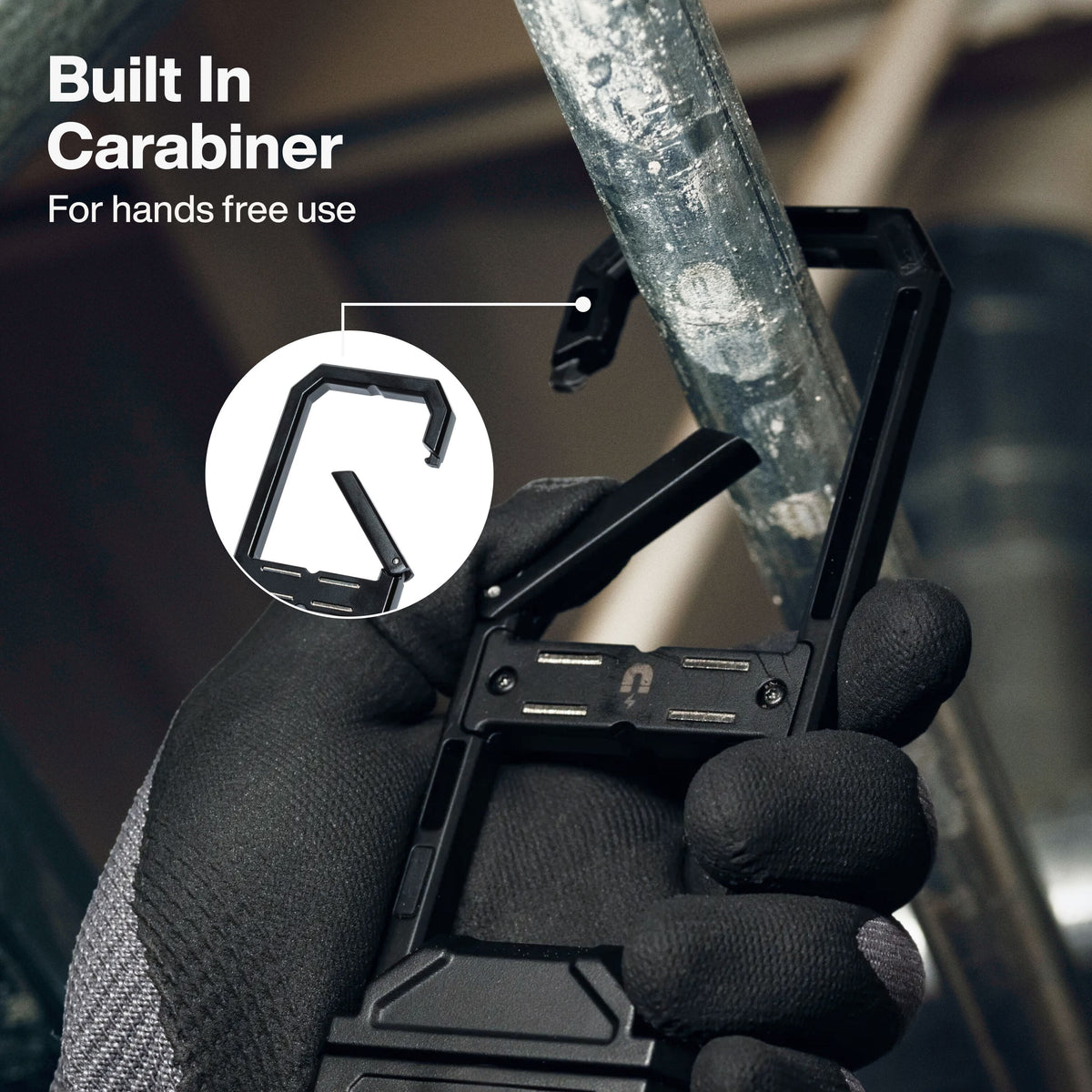 Hand-gloved worker using the built-in aluminum carabiner clip on Klein 56079 work light to hang it securely from a steel pipe.