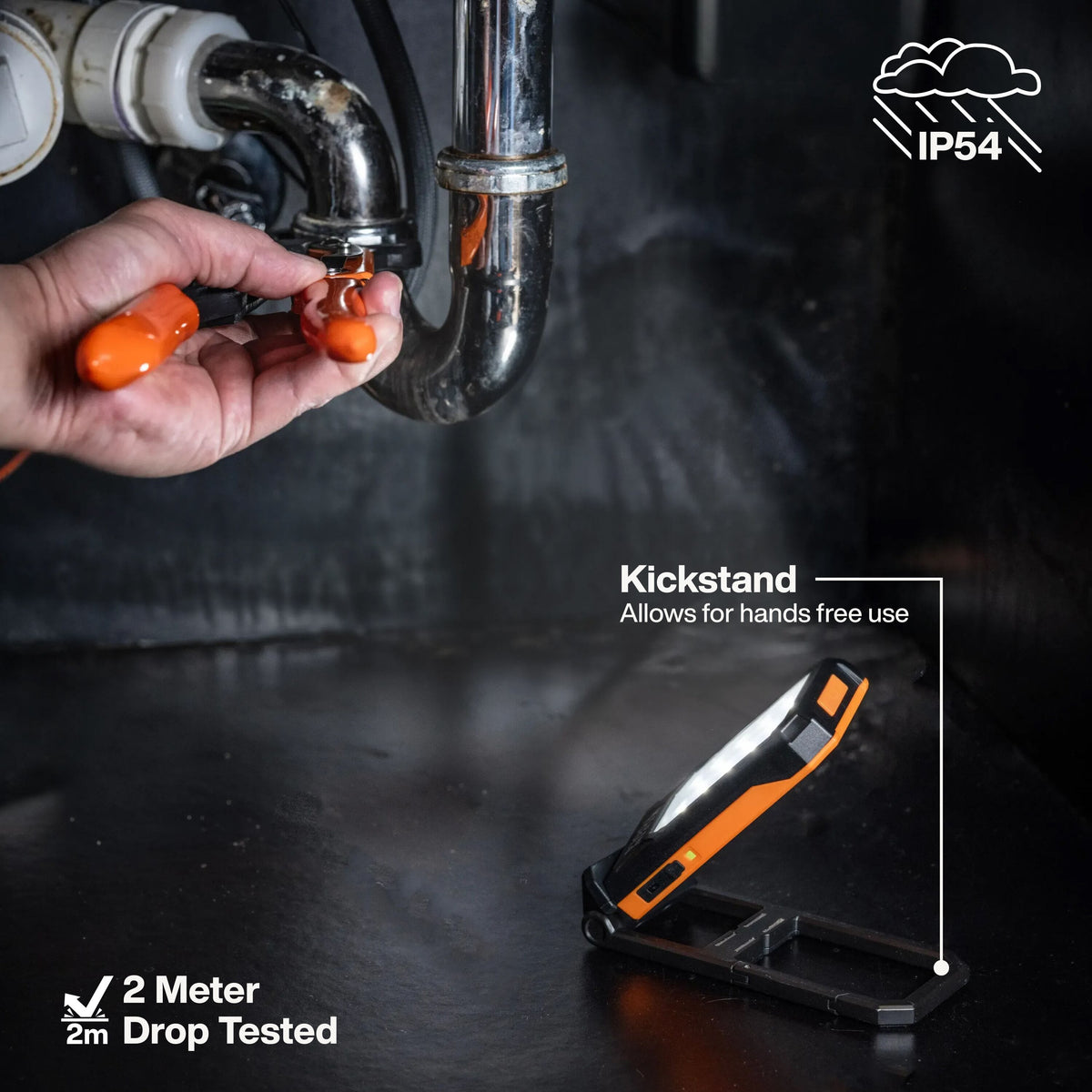 Plumber utilizing the prop kickstand on Klein 56079 light while working under a sink, highlighting IP54 water resistance and 2-meter drop protection.