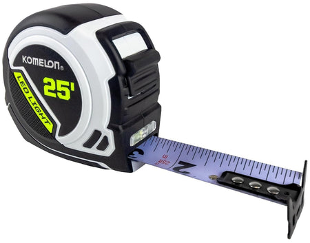 Studio view of the Komelon 25-foot LED tape measure featuring a black and white compact case with the blade slightly extended to show the high-visibility white surface and built-in LED light.