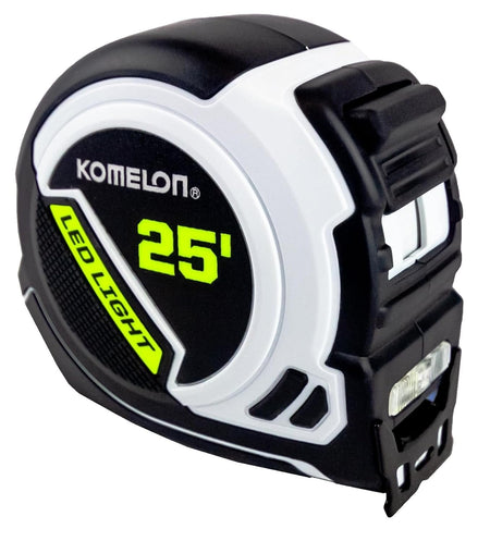 Angled studio view of the Komelon LED tape measure showing the ergonomic black and white casing, the slide lock mechanism, and the side profile with the rechargeable battery housing.