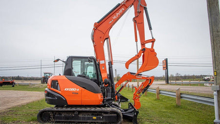 Kubota KX080-4 Power Utility Excavator resting on a large mound of dirt.