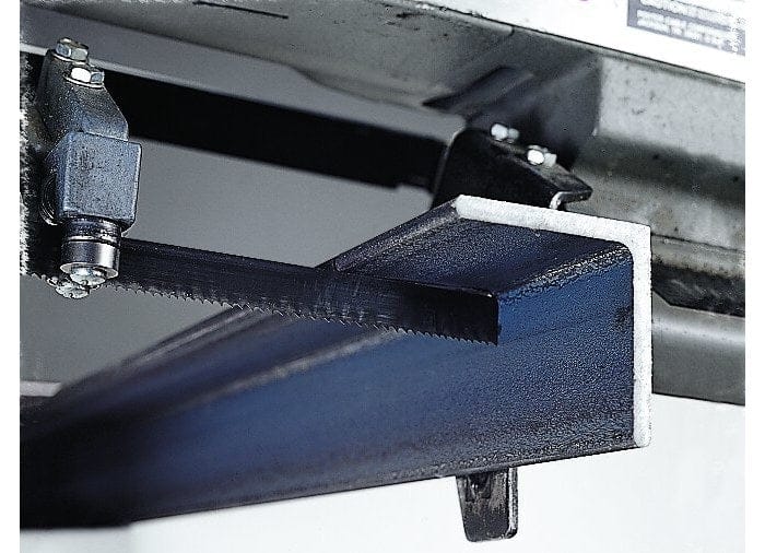 Close-up of a Lenox Wolf-Band portable band saw blade mounted in a tool, shown cutting through a piece of black structural metal with the guide bearings visible.