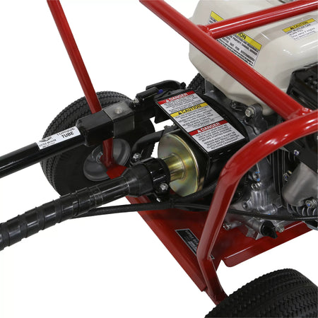 A detailed close-up shot focusing on the heavy-duty drive connection of the Little Beaver post hole digger power head machine, showcasing safety warning decals, the clutch drum housing, and the secure torque tube mounting bracket.