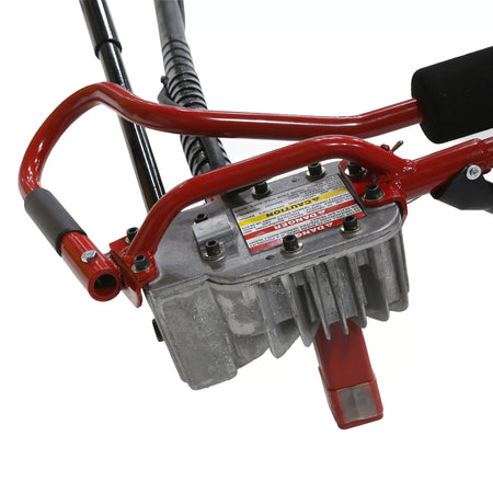 Close-up detailed image of the heavy-duty cast aluminum gear reduction transmission head located on the operator handle assembly, featuring prominent hazard warning texts and structural hex bolts.