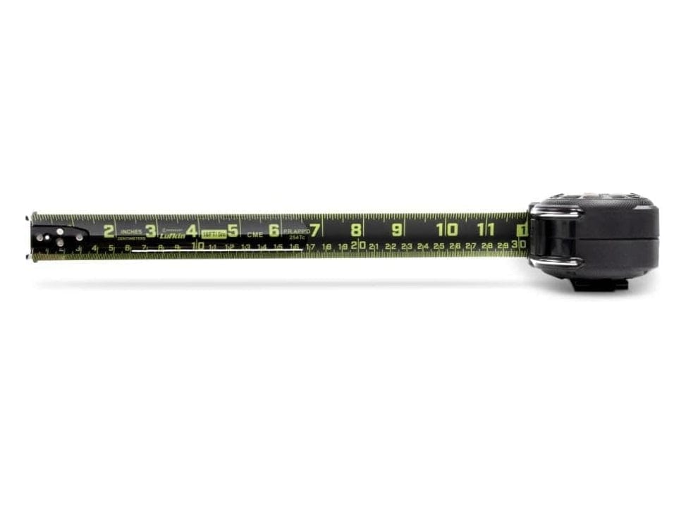 A top-down studio shot of the Lufkin Shockforce G2 tape measure. The black and green Nite Eye blade is extended horizontally, showing both SAE (inches) and metric (centimeters) markings.