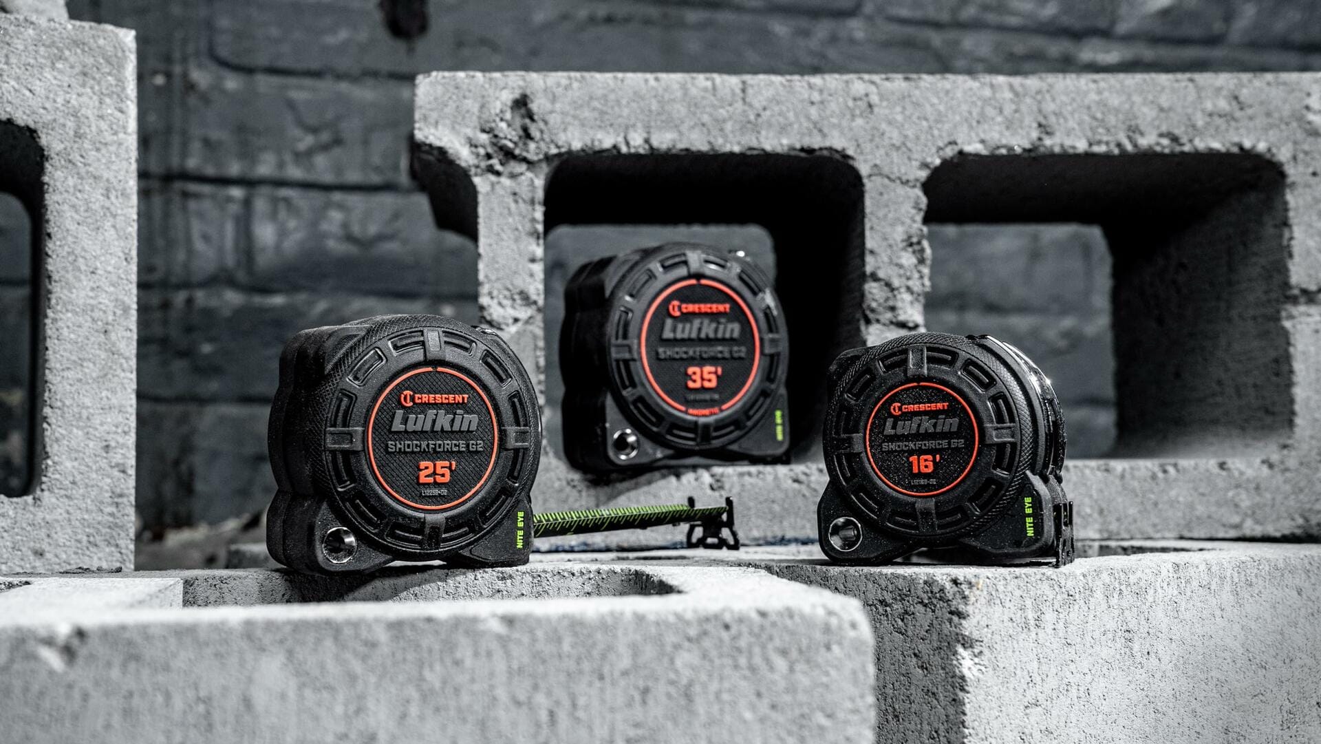 Three Lufkin Shockforce G2 tape measures (16-foot, 25-foot, and 35-foot) displayed on concrete cinder blocks in a construction jobsite setting.