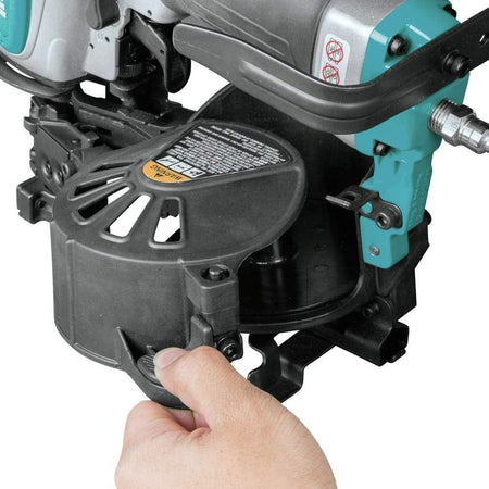 A close-up action shot of a hand opening the one-step adjustable canister system on the Makita AN454 roofing nailer.