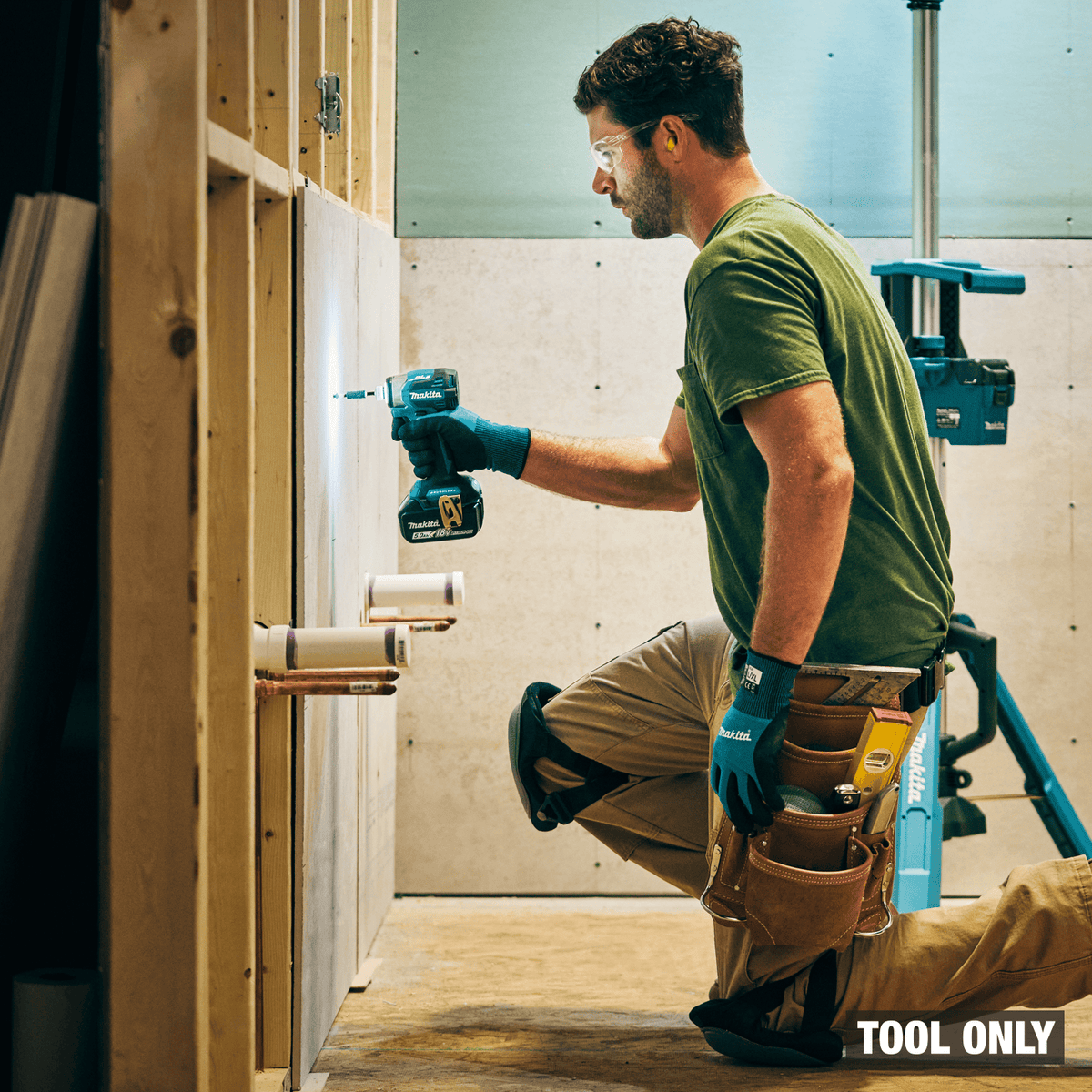 Makita XDT20Z cordless impact driver illuminating wall studs with 360-degree LED ring during drywall installation.