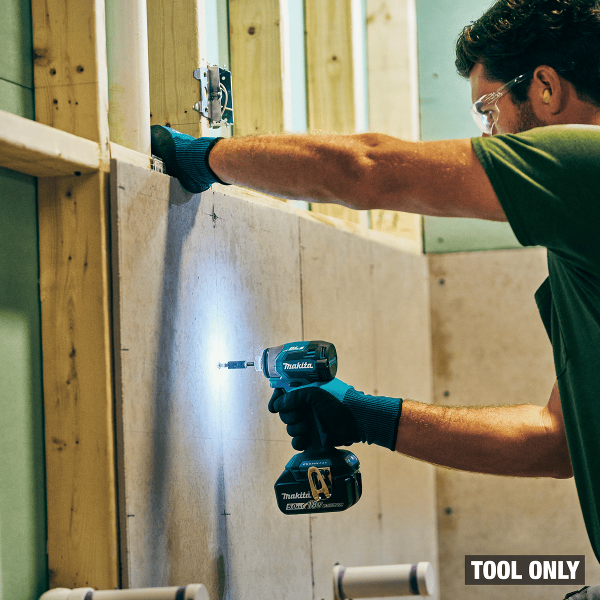 Drywall installer using Makita XDT20 impact driver with LED ring light to sink fasteners into framing studs.