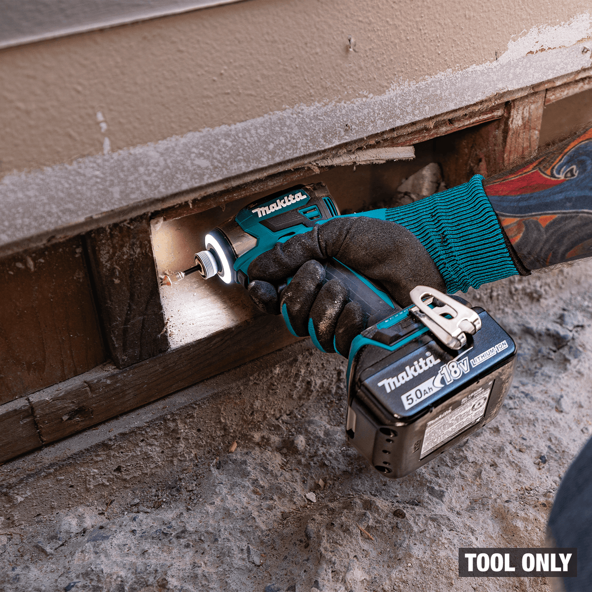 Contractor reaching into a tight foundation crawlspace cutout using compact Makita XDT20 cordless impact driver.