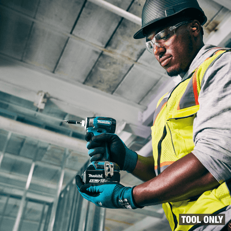 Construction worker holding a compact Makita XDT20 18V LXT brushless impact driver on a commercial jobsite.