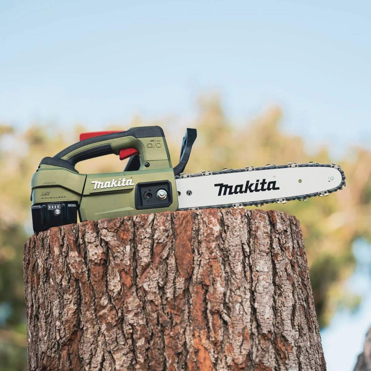 Makita Outdoor Adventure top handle chain saw positioned on a large stump, highlighting the 12 inch bar and 18V LXT battery for off-grid trail maintenance.