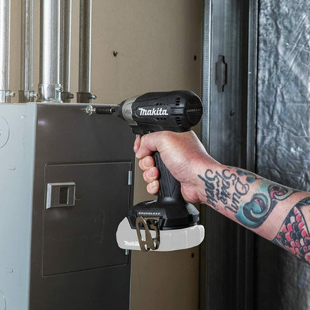 The Makita impact driver being used by a tradesperson to fasten conduit fittings to an electrical panel.