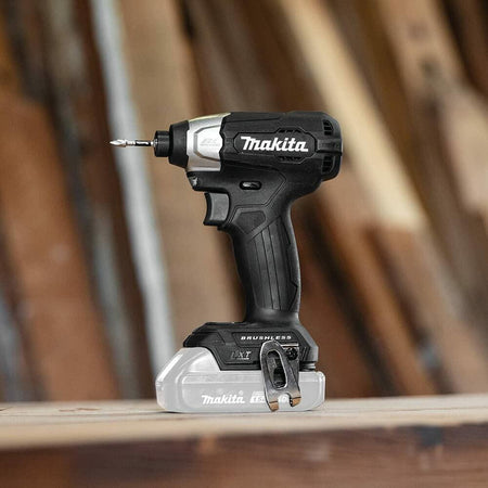 The Makita XDT18ZB impact driver resting on a wooden workbench in a workshop setting.