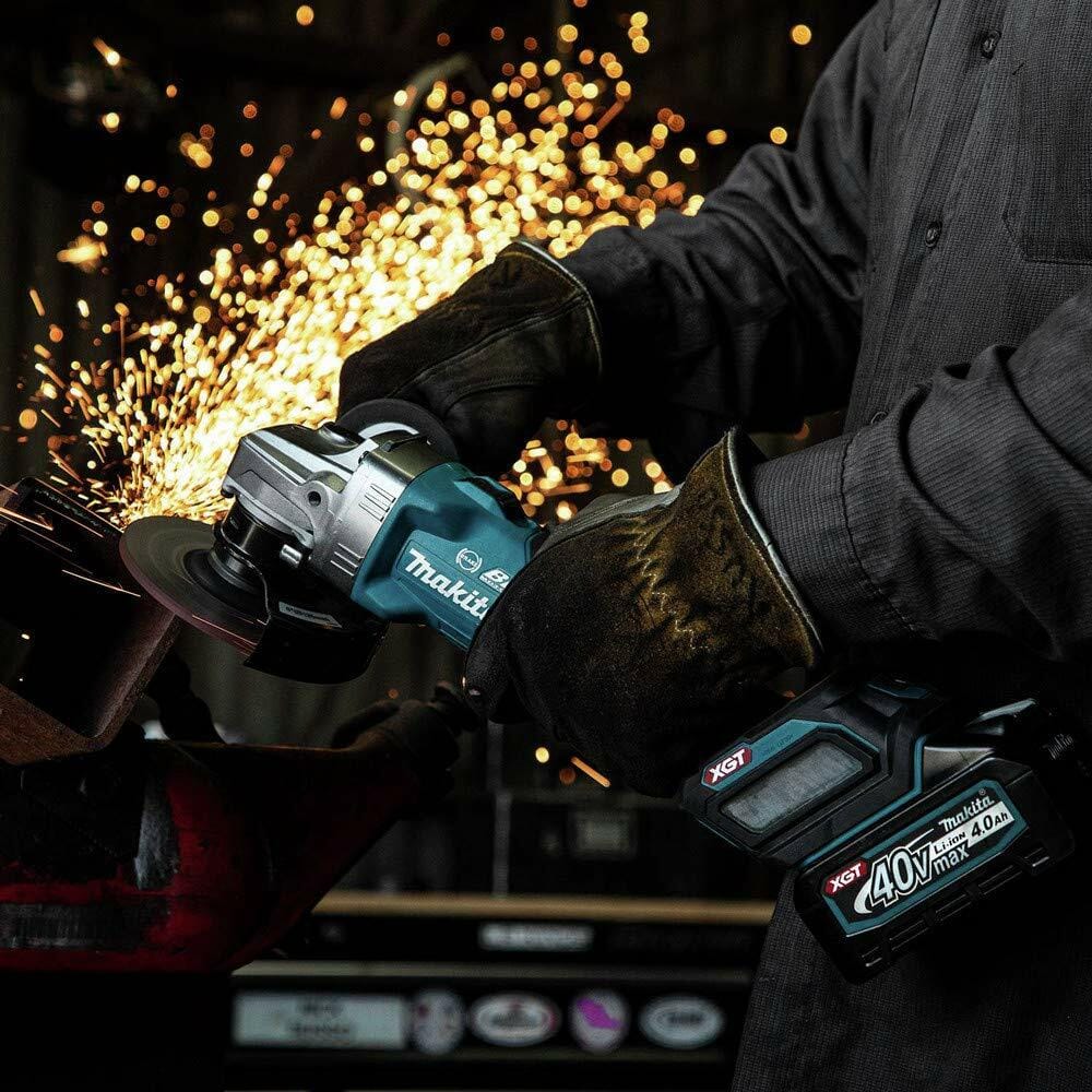 Makita GAG04 angle grinder in use cutting metal; sparks visible, user wearing gloves and long sleeves, tool labeled with 40V Max XGT 4.0Ah battery.