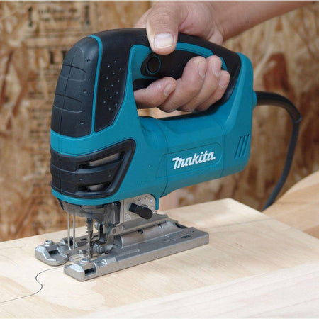 Close-up of the Makita 6.3 AMP jig saw cutting through a piece of hardwood, demonstrating the effective built-in dust blower clearing sawdust from the illuminated cut line.