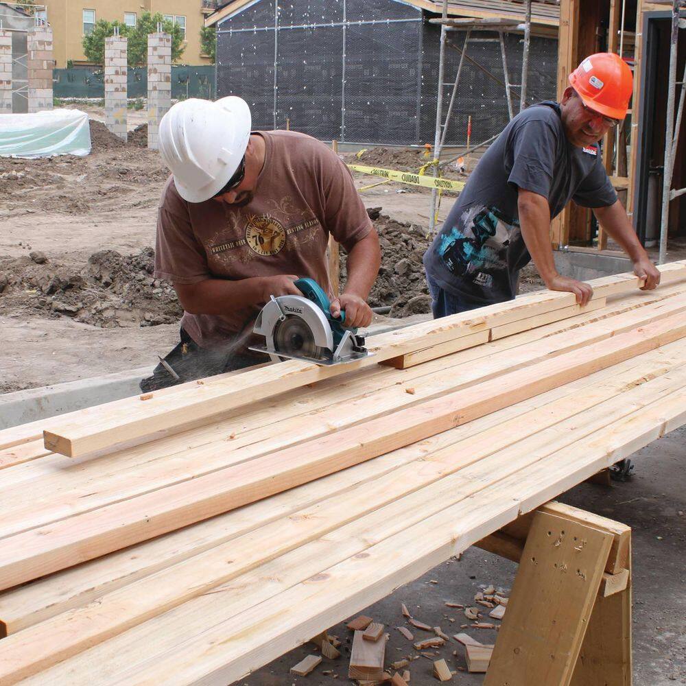 Construction workers on a jobsite using the Makita 5007FA circular saw to cut through stacked lumber, emphasizing efficiency and performance.